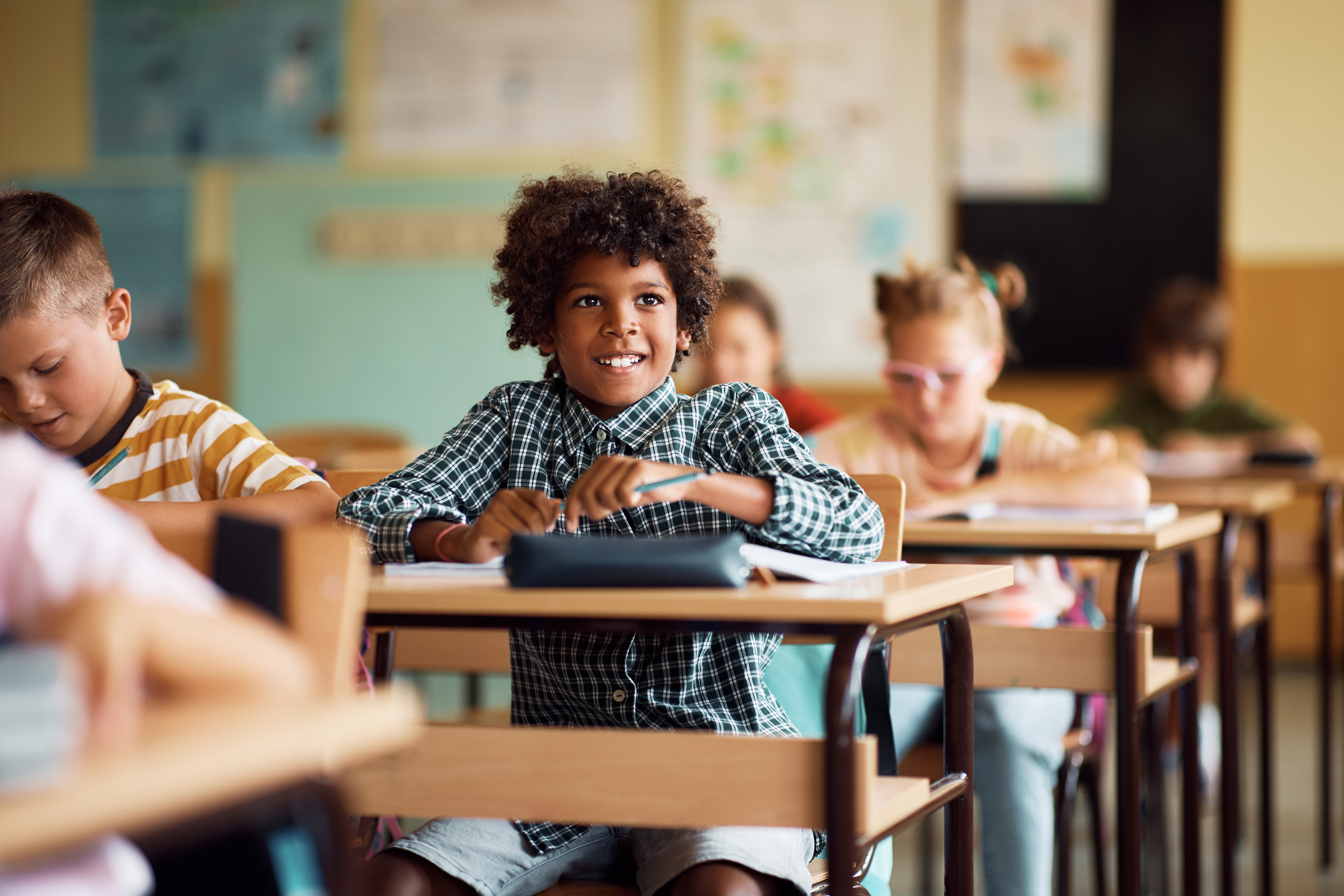 Happy black schoolboy attending a class in elementary school.