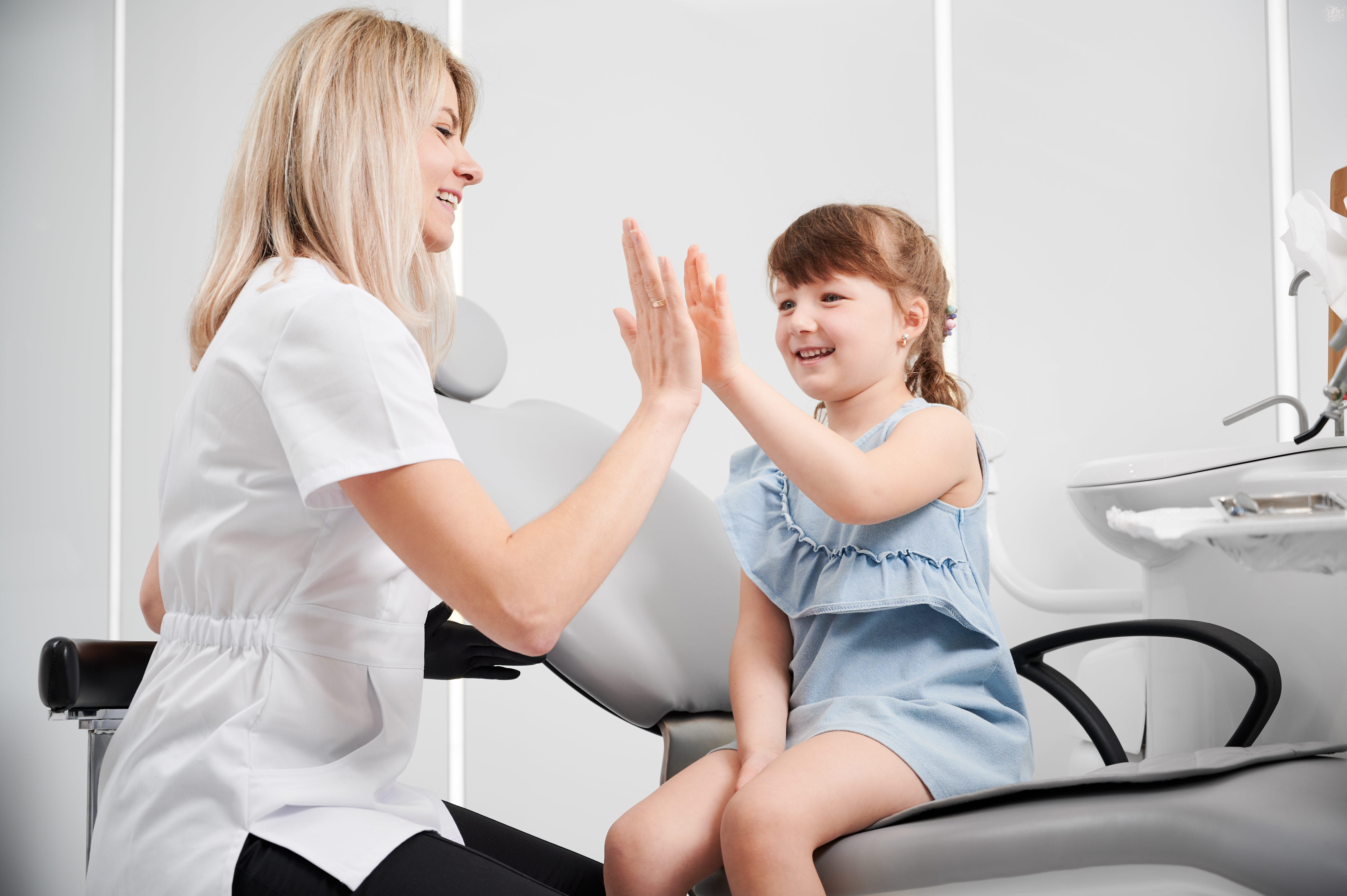 Happy kid at dentist office giving high five to a dentist