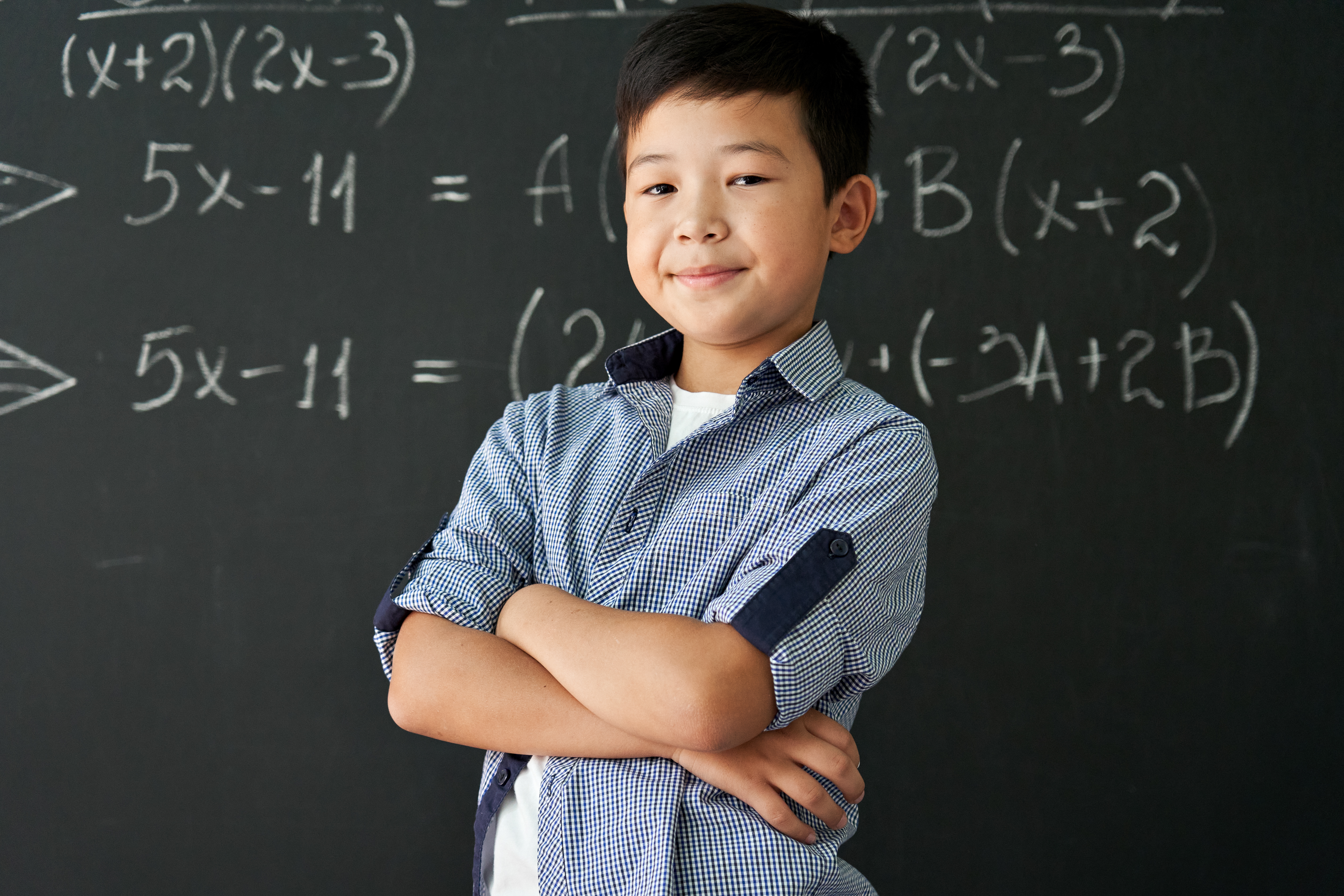 Portrait of happy proud asian boy standing on chalkboard background.