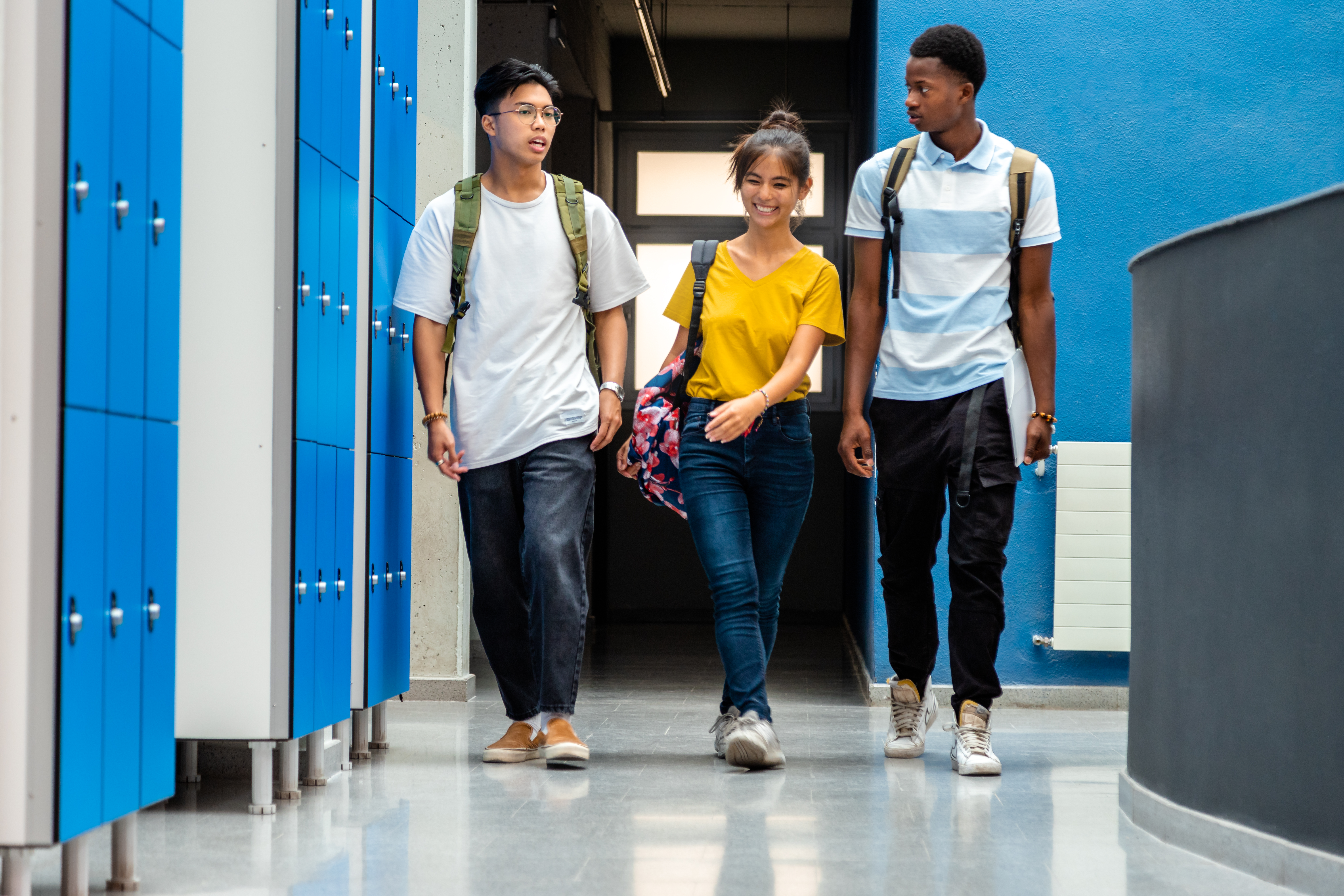 ultiracial teen high school students changing classes walking in school corridor. Back to school.